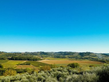 Tepeler, tarlalar ve çayırlar - tipik Toskana manzarası, İtalya. Seyahat, doğa ve tarım kavramı. Güneşli bir sonbahar günü, İtalya 'da tatiller. Boşluğu kopyala.