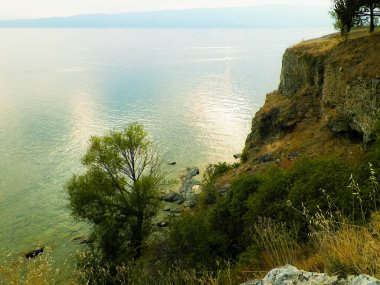 Ochrid Gölü 'nün güzel suları doğanın arka planıdır. Ochrid, Avrupa 'daki en eski göldür. Yüksek uçurumlar ve Akdeniz doğası.