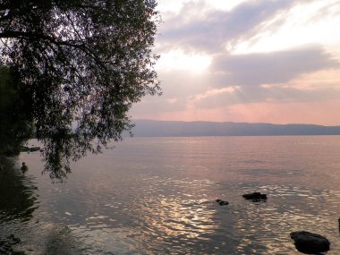 Ochrid Gölü üzerinde gün batımı. Ochrid Gölü 'nün güzel sularındaki güneşin yansıması. Doğadaki güzellik kavramı.