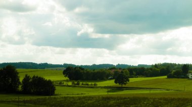 Rainy day over green hills and meadows of Kashubian Region, Poland. Copy space on cloudy sky.