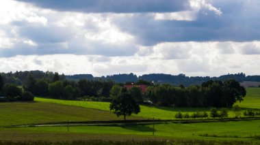 Rainy day over green hills and meadows of Kashubian Region, Poland. Copy space on cloudy sky.