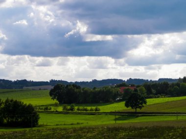 Rainy day over green hills and meadows of Kashubian Region, Poland. Copy space on cloudy sky.
