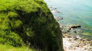 Karadeniz kıyısındaki kayalıklarda yeşil çimenler. Romanya 'nın Dobrogea bölgesinin Vama Veche kentindeki kayalıkların manzarası ve plajlar. Doğa ve seyahat kavramı.