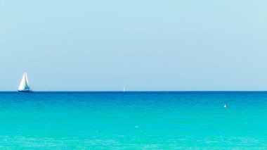 A boat in the turquoise waters of the Mediterranean Sea. Copy space on blue sky. Travel and leisure concept.