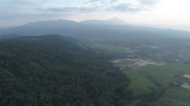 Banyumas, Central Java, Endonezya 'da bulutlu bir sabahta tepelerin ve dağların güzel görüntüsü. 4K Drone-124; Sawah berselimutkan awan di pagi hari