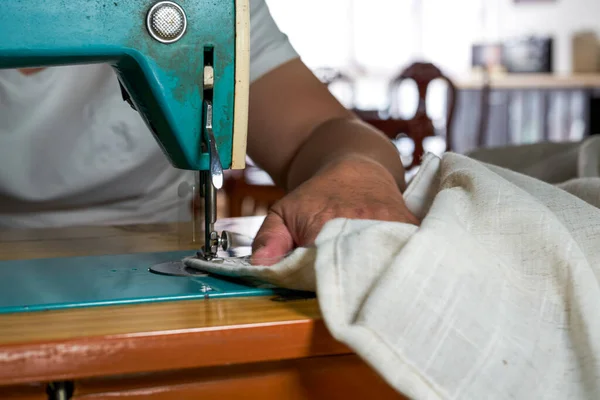 A tailor using a traditional household sewing machine