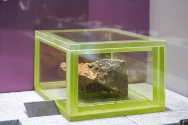 Radyasyon geçirmez cam bir kapta saklanan uranyum cevherinin yakın plan görüntüsü.