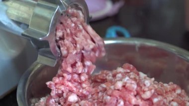 A commercial meat grinder machine in operation, churning minced meat