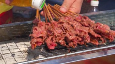 A person grilling outdoors, grilled beef kebabs