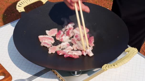 Person Frying Pork Belly Cast Iron Pan Outdoors — Vídeo de Stock