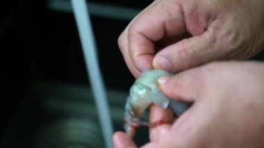 Mutfaktaki bir aşçı taze karidesleri temizliyor.