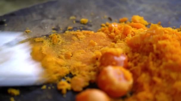 シェフは卵の黄身のグラタンを作るために台所でナイフで塩卵黄を粉砕しています — ストック動画