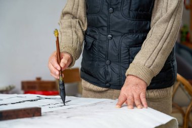 Eski bir Çinli hat yazarı yazı ve kaligrafi çalışmaları yaratıyor. Tercümesi: geçmişi devam ettir ve geleceği aç.