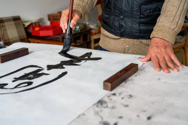 Stock image An old Chinese calligrapher is creating and writing calligraphy works.Translation: carry on the past and open up the future.