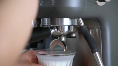 Profesyonel bir barista latte yapmak için kahve makinesi kullanıyor.
