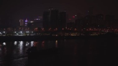 Büyük bir kum madeni gemisi gece şehir nehrinde yol alıyor.