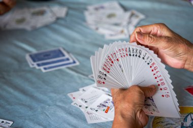 Bir grup yaşlı insan oturup poker oynuyor.