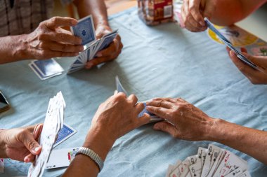 Bir grup yaşlı insan oturup poker oynuyor.