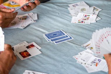 Bir grup yaşlı insan oturup poker oynuyor.