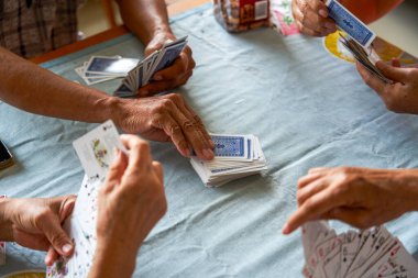 Bir grup yaşlı insan oturup poker oynuyor.