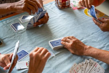 Bir grup yaşlı insan oturup poker oynuyor.