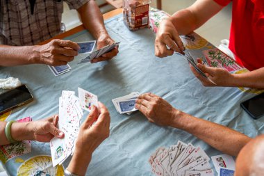 Bir grup yaşlı insan oturup poker oynuyor.