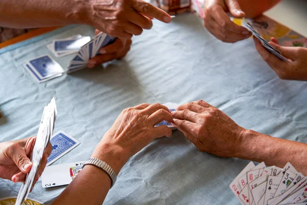 A group of old people sit around and play poker card