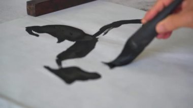 Ünlü bir Çinli kaligraf bir fırçayla yazı yazar, bir hat çalışması yaratır.