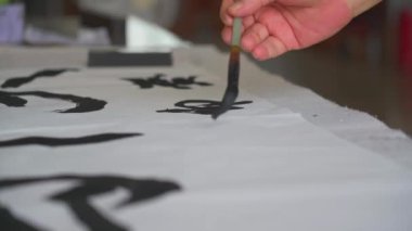 Ünlü bir Çinli kaligraf bir fırçayla yazı yazar, bir hat çalışması yaratır.