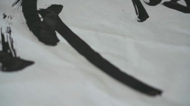 Ünlü bir Çinli kaligraf bir fırçayla yazı yazar, bir hat çalışması yaratır.