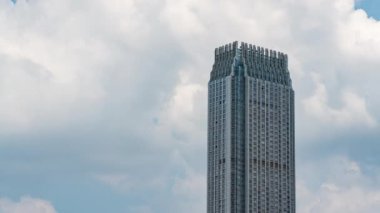 Şehirde mavi gökyüzü ve beyaz bulutları olan yüksek katlı modern bir binanın hızlandırılmış fotoğrafları.
