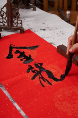 Eski bir kaligraf Çin Ejderha Yılı 'nda çiftler yazar. Çeviri: Altın Ejder size yeni yılda iyi şanslar diler..