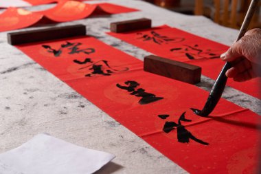 Eski bir kaligraf Çin Ejderha Yılı 'nda çiftler yazar. Çeviri: Uğurlu enerji bereket getirir ve zenginlik bolluk getirir..