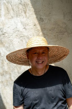 Asyalı bir adam verandadan gelen güneş ışığının altında duruyor.