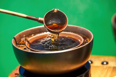 Geleneksel Çin bakır tenceresi Pu 'er çayı pişiriyor, ocağın etrafında çay yapıyor.