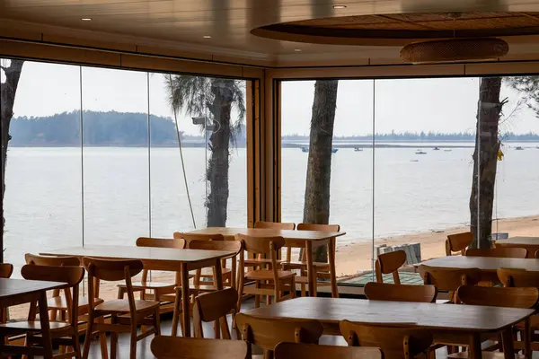 Deniz kıyısındaki bir restoranda ahşap masalar ve sandalyelerin yakın çekimi.