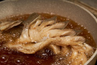 Mutfakta bir şef kızarmış balık yapıyor, bütün bir balığı kızartıyor.