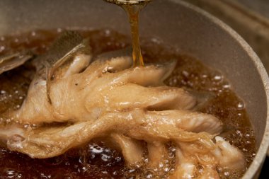 Mutfakta bir şef kızarmış balık yapıyor, bütün bir balığı kızartıyor.