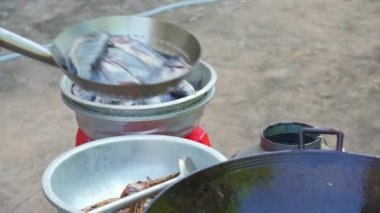 Bir şef büyük bir yağ tavasında balık kızartıyor.