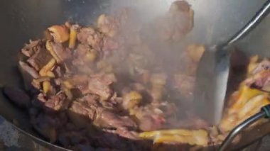 Bir şef büyük bir tencerede ördek eti pişiriyor.