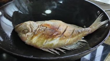 Çinli bir şef demir tavada balık kızartıyor.