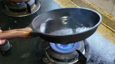 Bir şef tavada sarımsaklı lahana kızartıyor.