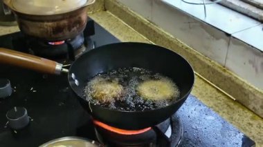 Bir şef tavada kalamar halkaları kızartıyor.