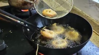 Bir şef tavada kalamar halkaları kızartıyor.