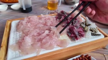 Bir lokanta Hengxian saşimi yiyor, içinde bol saşimi ve malzemeler var..