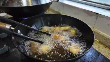 Kızartma tavasında tavuk kızartma yapan bir şefin yavaş hareketi.