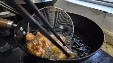 Kızartma tavasında tavuk kızartma yapan bir şefin yavaş hareketi.