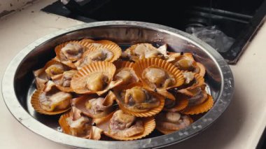 Kantonlu bir şef sarımsak soslu istiridye hazırlar.