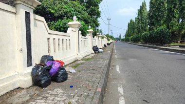 Şehir yolundaki kaldırımda çöp torbası yığını