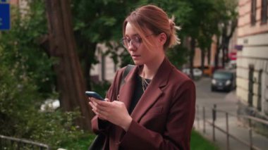 Sokakta cep telefonunu kullanan gözlüklü güzel beyaz bir kadının portresini yakından çek. Yüksek kalite 4k görüntü